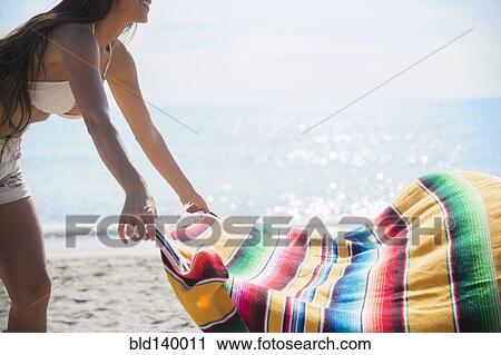 Caucasian woman spreading blanket on beach View Large Photo Image Stock Image - Caucasian woman spreading blanket on beach. Fotosearch