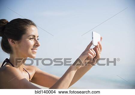 Caucasian woman taking selfie with cell phone at beach View Large Photo Image Picture - Caucasian woman taking selfie with cell phone at beach. Fotosearch