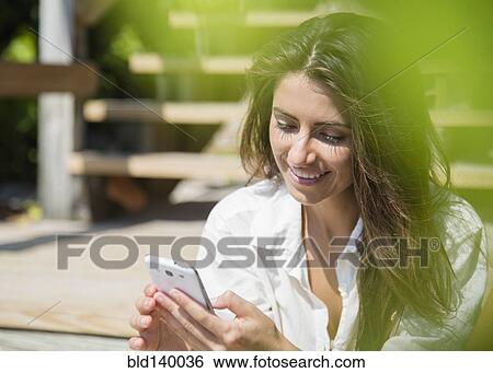 Stock Photograph - Caucasian woman using cell phone outdoors. Fotosearch