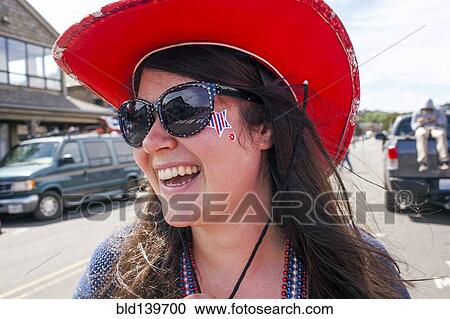 Stock Image - Caucasian woman wearing cowboy hat and face paint in street. Fotosearch