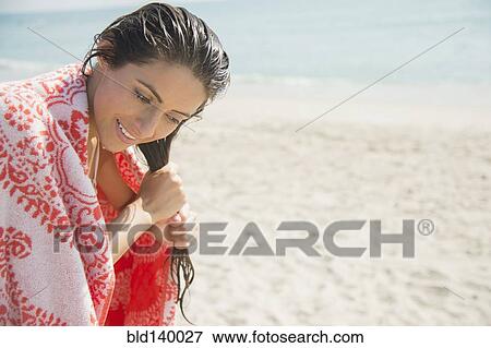 Stock Photo - Caucasian woman wringing hair on beach. Fotosearch