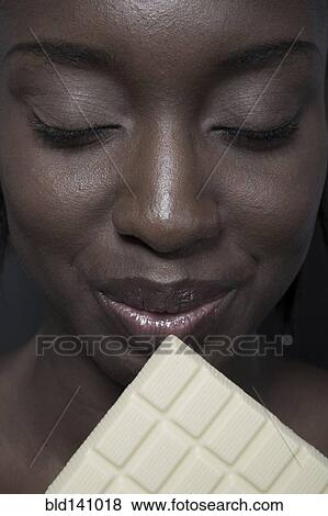 Close up of black woman eating bar of white chocolate View Large Photo Image Stock Photo - Close up of black woman eating bar of white chocolate. Fotosearch