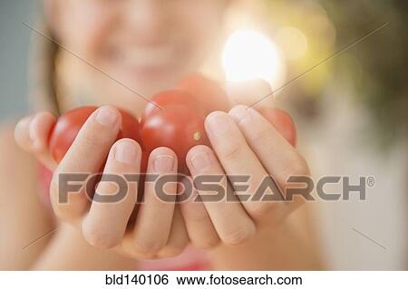 Stock Photograph - Close up of Caucasian girl holding handful of tomatoes. Fotosearch