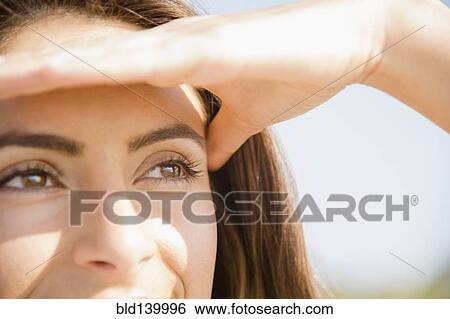 Stock Photograph - Close up of Caucasian woman shielding eyes from sun. Fotosearch