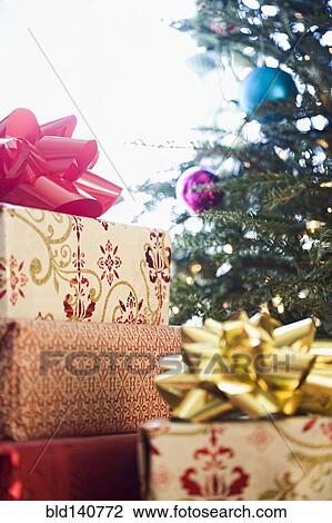 Stock Image - Close up of wrapped gifts under Christmas tree. Fotosearch