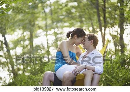 Stock Photo - Couple rubbing noses on bench in park. Fotosearch