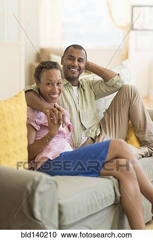 Couple smiling on sofa in living room View Large Photo Image Stock Image - Couple smiling on sofa in living room. Fotosearch