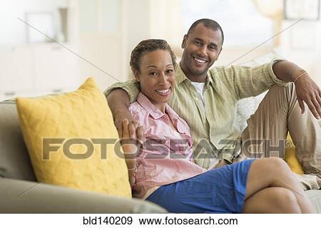 Stock Photo - Couple smiling on sofa in living room. Fotosearch