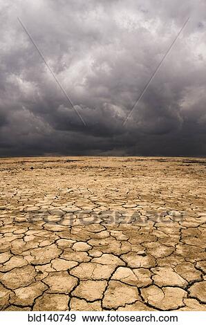 Cracked earth under cloudy sky in desert landscape View Large Photo Image Stock Photo - Cracked earth under cloudy sky in desert landscape. Fotosearch