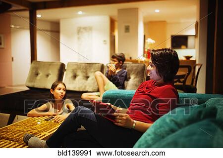 Family relaxing together in living room View Large Photo Image Stock Image - Family relaxing together in living room. Fotosearch