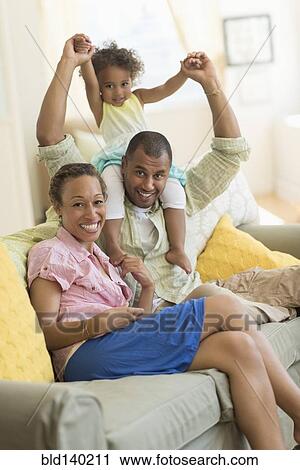 Family smiling on sofa in living room View Large Photo Image Stock Image - Family smiling on sofa in living room. Fotosearch