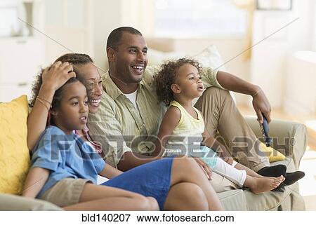 Stock Photo - Family watching television together in living room. Fotosearch