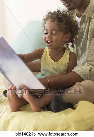 Stock Photography - Father and daughter reading book on bed. Fotosearch