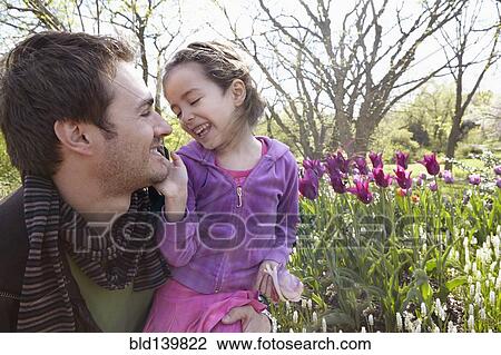 Stock Image - Father carrying daughter in park. Fotosearch