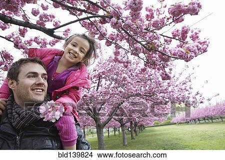 Father carrying daughter on shoulders in park View Large Photo Image Picture - Father carrying daughter on shoulders in park. Fotosearch