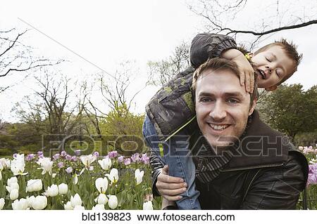Father carrying son in park View Large Photo Image Stock Image - Father carrying son in park. Fotosearch