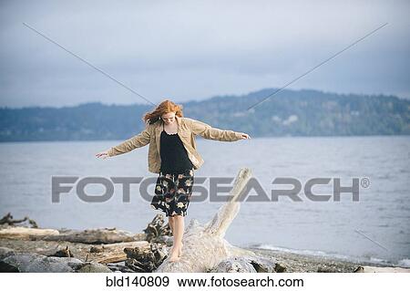 Girl balancing on driftwood on beach View Large Photo Image Stock Photo - Girl balancing on driftwood on beach. Fotosearch