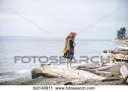 Girl standing on driftwood on beach View Large Photo Image Stock Image - Girl standing on driftwood on beach. Fotosearch