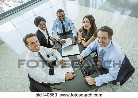 Stock Image - High angle view of business people smiling in meeting. Fotosearch
