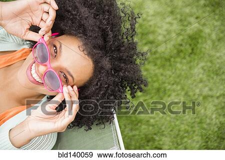 High angle view of woman holding sunglasses in chair outdoors View Large Photo Image Stock Photo - High angle view of woman holding sunglasses in chair outdoors. Fotosearch