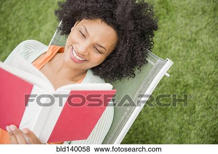 High angle view of woman reading book in chair outdoors View Large Photo Image Stock Photo - High angle view of woman reading book in chair outdoors. Fotosearch