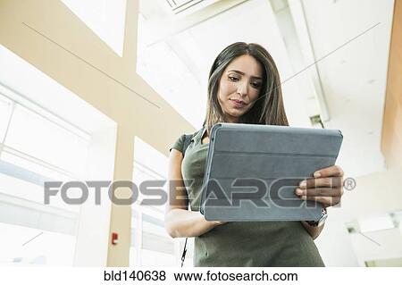 Stock Photo - Hispanic businesswoman using digital tablet in office. Fotosearch