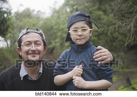 Picture - Hispanic father and son hugging in park. Fotosearch