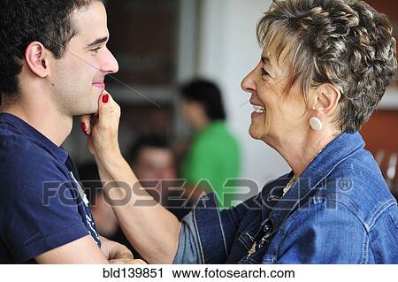 Stock Image - Hispanic grandmother pinching grandsons face. Fotosearch