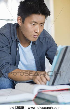 Korean man doing homework with digital tablet View Large Photo Image Stock Image - Korean man doing homework with digital tablet. Fotosearch