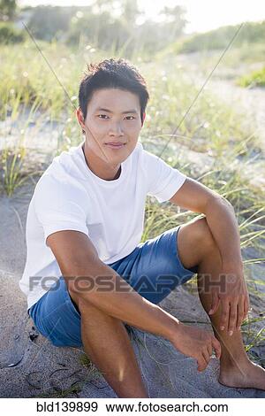 Stock Photo - Korean man sitting on beach. Fotosearch