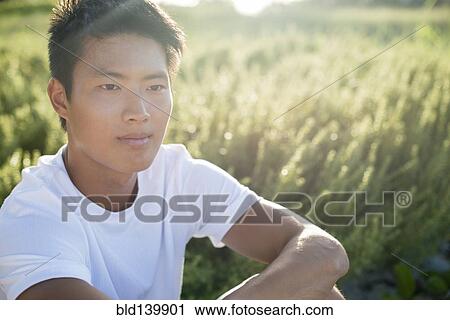 Stock Image - Korean man sitting outdoors. Fotosearch