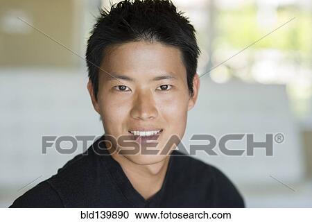 Stock Image - Korean man smiling indoors. Fotosearch