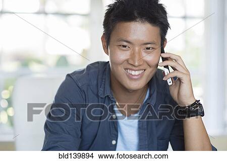 Korean man talking on cell phone indoors View Large Photo Image Picture - Korean man talking on cell phone indoors. Fotosearch