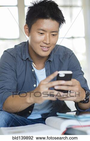 Korean man using cell phone and doing homework View Large Photo Image Stock Image - Korean man using cell phone and doing homework. Fotosearch