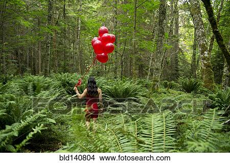 Korean woman holding red balloons in lush forest View Large Photo Image Picture - Korean woman holding red balloons in lush forest. Fotosearch