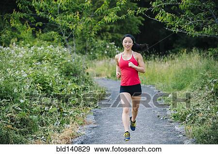 Stock Photo - Korean woman running on remote path. Fotosearch