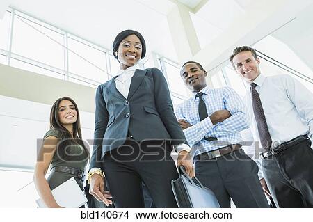 Low angle view of business people smiling in office lobby View Large Photo Image Picture - Low angle view of business people smiling in office lobby. Fotosearch
