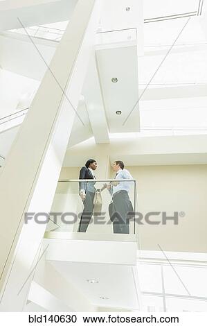 Low angle view of business people talking on office balcony View Large Photo Image Stock Image - Low angle view of business people talking on office balcony. Fotosearch