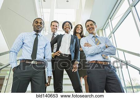 Stock Image - Low angle view of business people smiling on office staircase. Fotosearch