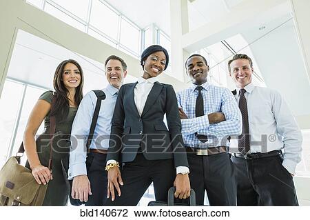 Stock Image - Low angle view of business people smiling in office lobby. Fotosearch