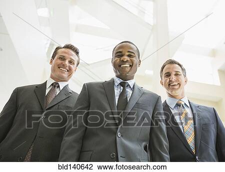 Low angle view of businessmen smiling in office View Large Photo Image Stock Image - Low angle view of businessmen smiling in office. Fotosearch