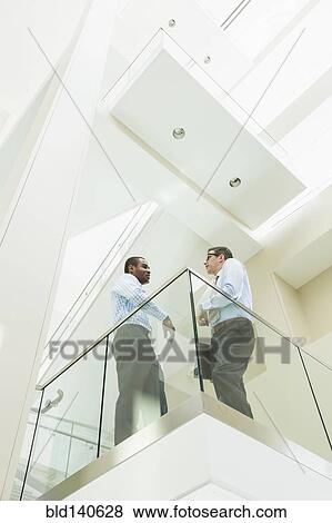 Low angle view of businessmen talking on office balcony View Large Photo Image Stock Photo - Low angle view of businessmen talking on office balcony. Fotosearch