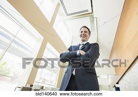 Low angle view of Caucasian businessman standing in office View Large Photo Image Stock Image - Low angle view of Caucasian businessman standing in office. Fotosearch