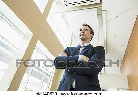 Stock Photo - Low angle view of Caucasian businessman standing in office. Fotosearch