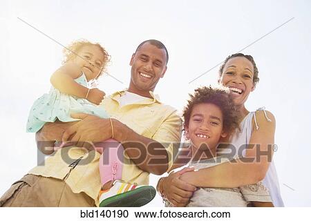 Low angle view of family smiling together outdoors View Large Photo Image Stock Image - Low angle view of family smiling together outdoors. Fotosearch