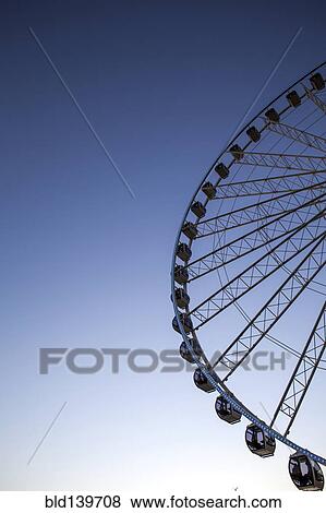 Stock Photo - Low angle view of ferris wheel against blue sky. Fotosearch