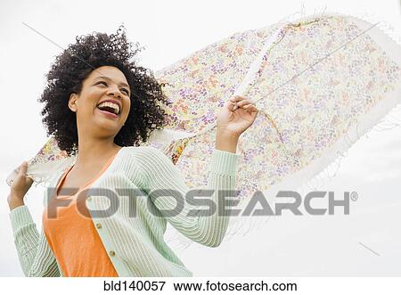 Stock Photo - Low angle view of woman playing with scarf outdoors. Fotosearch