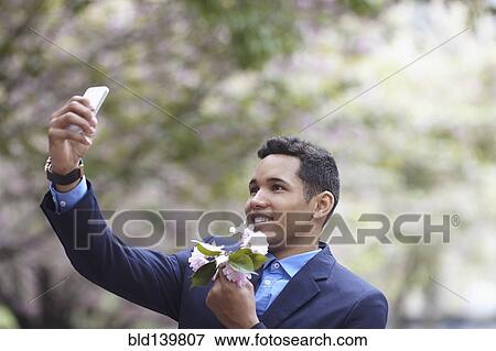 Man in suit taking cell phone selfie while holding flowers View Large Photo Image Stock Photo - Man in suit taking cell phone selfie while holding flowers. Fotosearch