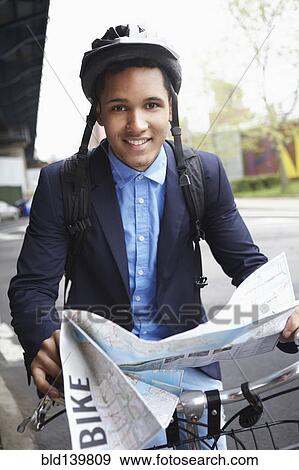 Stock Photo - Man on bicycle reading map on city street. Fotosearch