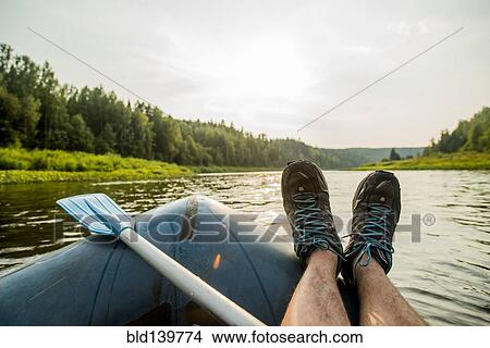 Man resting feet on boat in lake View Large Photo Image Picture - Man resting feet on boat in lake. Fotosearch